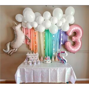 Rainbow backdrop with stars added and unicorn caketopper with eyes